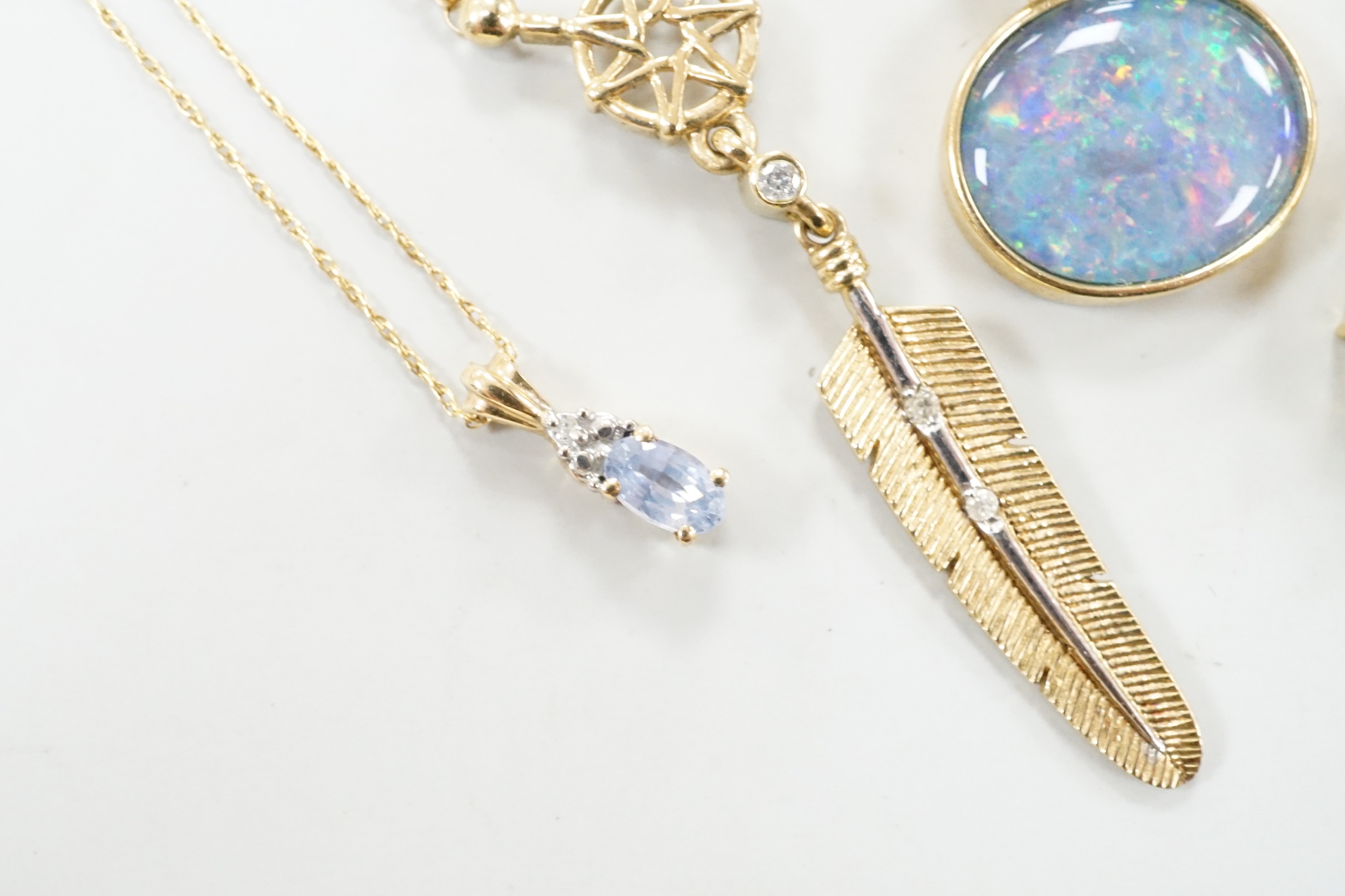 Three assorted modern 9ct or yellow metal and gem set pendants, on 9ct chains including opal doublet and blue topaz, feather shape and emerald set circular and a similar 10k pendant, on a 10k chain, longest 52cm, gross w